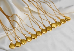 Vue à plat de 12 pendentifs constellations dorés sur soie blanche avec finition en or 18 carats