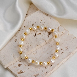 Bracelet fait main en perles d'eau douce et perles dorées sur plateau en pierre