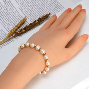 Bracelet élégant avec perles d'eau douce blanches et billes dorées sur fond vintage