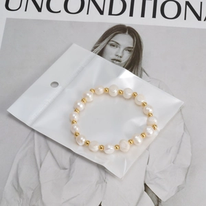 Bracelet en perles d'eau douce fait main avec billes dorées sur un fond de magazine de mode