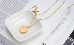 Détail du collier œil maléfique doré en acier inoxydable sur une coupelle en céramique