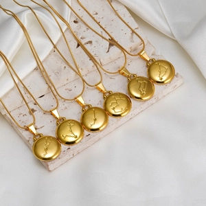 Detail of 18K gold-plated zodiac pendant necklaces featuring engraved constellation symbols