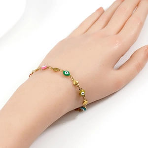 Close-up of gold chain bracelet with colorful evil eye beads and golden heart charms