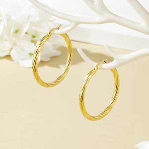 Elegant gold twisted rope hoop earrings displayed on a white decorative stand