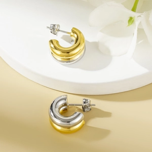 Two-tone gold and silver stainless steel C-shaped hoop earrings on a display stand
