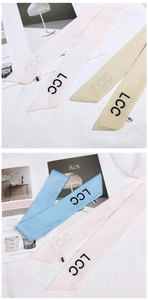 Detailed view of pastel satin hair scarves with LCC logo on textured fabric background