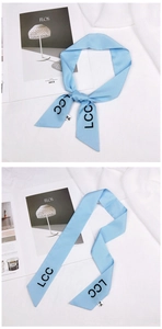 Close-up of light blue silk hair ribbon with LCC lettering and satin finish texture