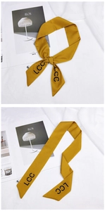 Detail of mustard yellow silk scarf featuring black LCC letter print and smooth texture