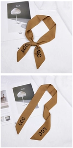 Detail of dark brown satin skinny scarf with black LCC letters and soft fabric texture