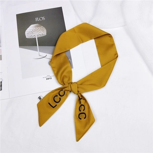 Chic mustard yellow skinny silk scarf with black letter print on white fabric background