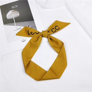 Mustard yellow silk-like bow headband with black letter print and elegant ribbon design