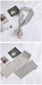 Gros plan d'un foulard étroit en soie à pois et rayures noir et blanc sur magazine