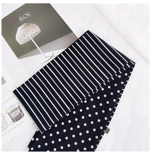 Détail d'un foulard en soie double face avec rayures noires et blanches et pois