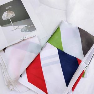 Carré de soie aux blocs de couleurs géométriques rouge, bleu marine et blanc sur une table