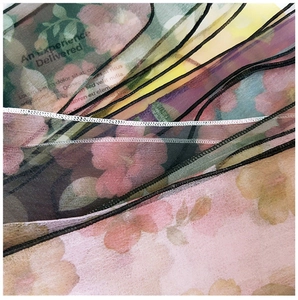 Detail of floral printed organza scarf featuring delicate stitched edges and sheer texture