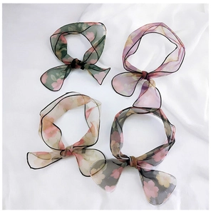 Close-up of four floral organza scarves with delicate bow ties and fine stitching details