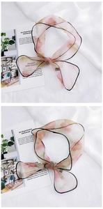 Detail of floral organza neck scarf tied in a bow with pink flower prints and black trim
