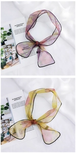 Detailed view of floral organza scarves in purple and yellow with fine black edges