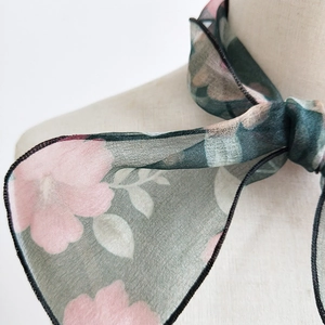Green floral organza scarf tied on a mannequin showing light translucent chiffon fabric