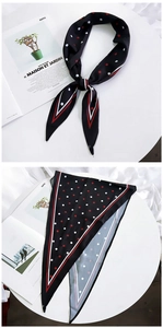 Detailed view of a black silk scarf featuring classic red and white polka dots and stripes