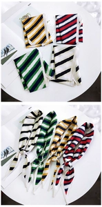 Detail of four striped twilly scarves in vibrant colors with a silky glossy texture