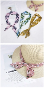 Floral print scarves tied on a straw hat and displayed in various patterns and colors