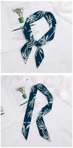 Detail of navy blue silk scarf with palm tree prints tied in a bow and flat layout