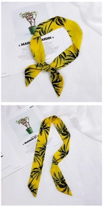 Close-up of yellow silk scarf with black palm tree prints tied in a stylish knot