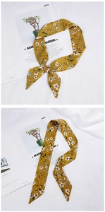 Close-up of bright yellow floral silk scarf tied as a delicate hair accessory or bag ribbon