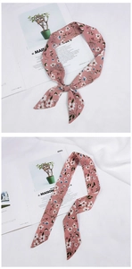 Detailed view of a pink floral silk scarf tied in a bow with elegant petal patterns