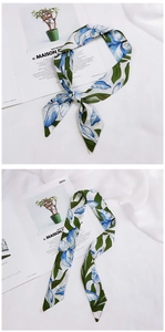 Detail of elegant white twilly scarf with blue floral print on soft fabric background
