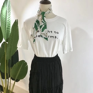 Three-piece set featuring a white graphic T-shirt, floral silk scarf, and black pleated skirt