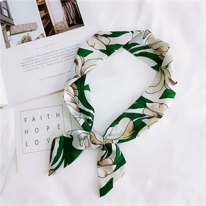 Detailed view of floral silk scarf with green leaves on a soft textured background