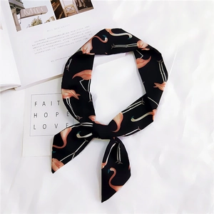 Close-up of black skinny scarf with pink flamingo print on white textured fabric
