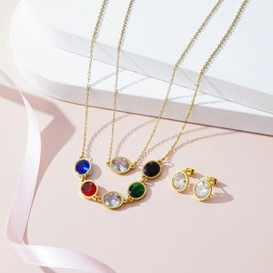 Luxury gold necklace set with colorful gemstones and matching studs on white podium