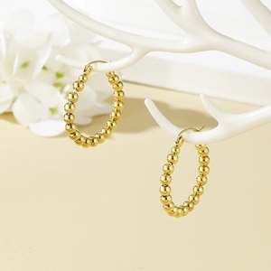 Vintage beaded gold-plated stainless steel hoop earrings on a white jewelry stand