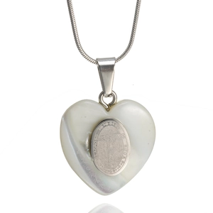 Macro detail of silver heart pendant with shell inlay and religious engraving