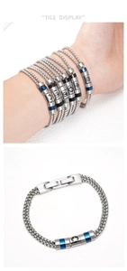 Macro detail of men's double-layer stainless steel chain bracelet with nautical engraved beads