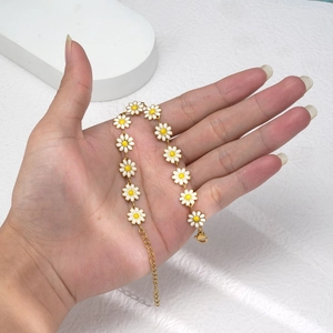 Bracelet marguerite élégant avec pétales blancs et chaîne dorée présenté à la main