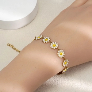 Bracelet marguerite doré élégant avec émail blanc pour femme porté sur le poignet