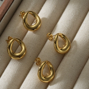 Minimalist 18k gold plated stainless steel teardrop earrings on a beige linen display