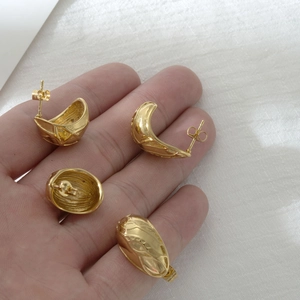 Gold pea irregular textured stainless steel earrings shown in a hand-held display