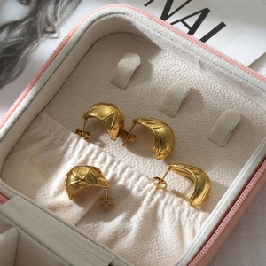Detail of gold pea-shaped C-earrings with diamond texture and smooth mirror finish