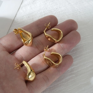 Boucles d'oreilles irrégulières géométriques en acier doré en forme de C en main