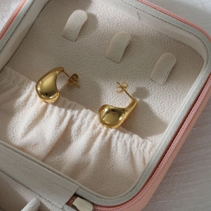 Boucles d'oreilles gouttes dorées polies présentées sur un écrin à bijoux en velours doux