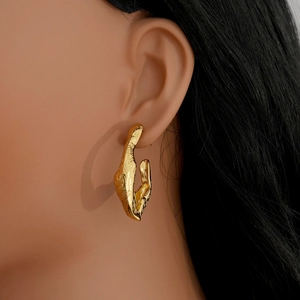 Close-up of golden irregular textured earrings with molten lava finish on a model
