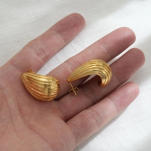 Macro shot of gold-plated striped teardrop earrings featuring a chunky C-shaped texture