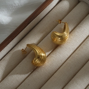 Close-up of gold chunky C-shaped hoop earrings with ribbed texture on jewelry box