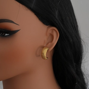 Close-up of golden stainless steel C-shaped earrings featuring a vintage woven texture