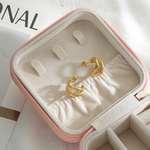 18k gold plated twisted C-shape stainless steel earrings on a pink jewelry box
